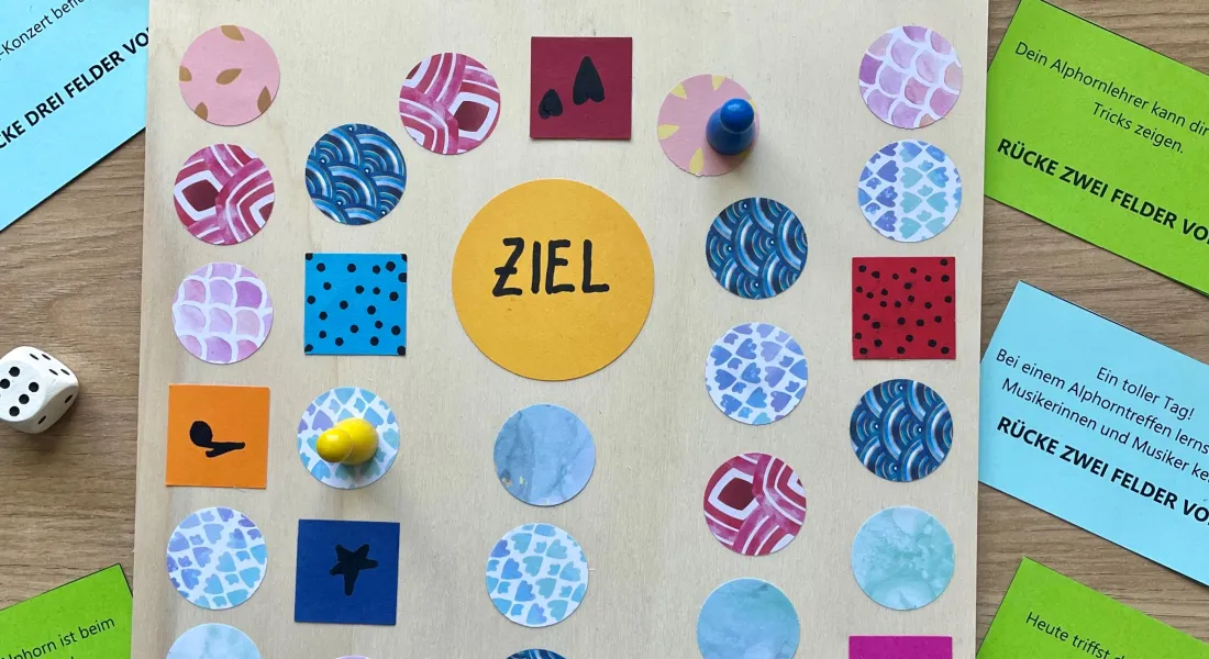 Ein fertig gestaltetes Brettspiel aus Holz mit aufgeklebten Spielfeldern aus buntem Papier.