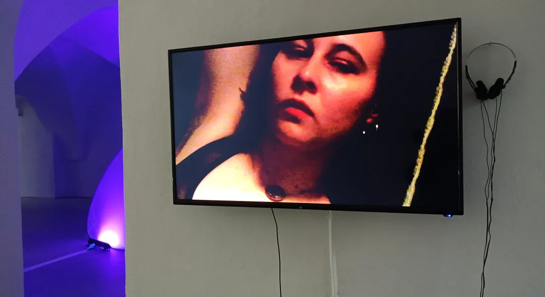 Weibliche Person mit geschlossenen Augen und ausgestreckten Armen auf einem Videoschirm