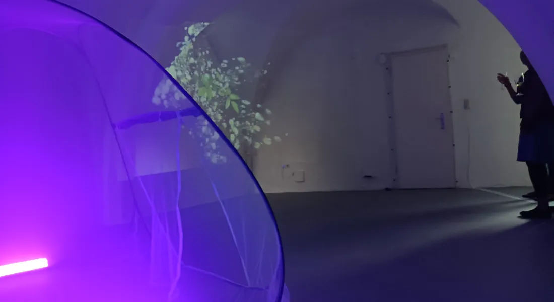 Zwei Personen mit Weingläsern betrachten eine Kunstausstellung in einem Gewölbe