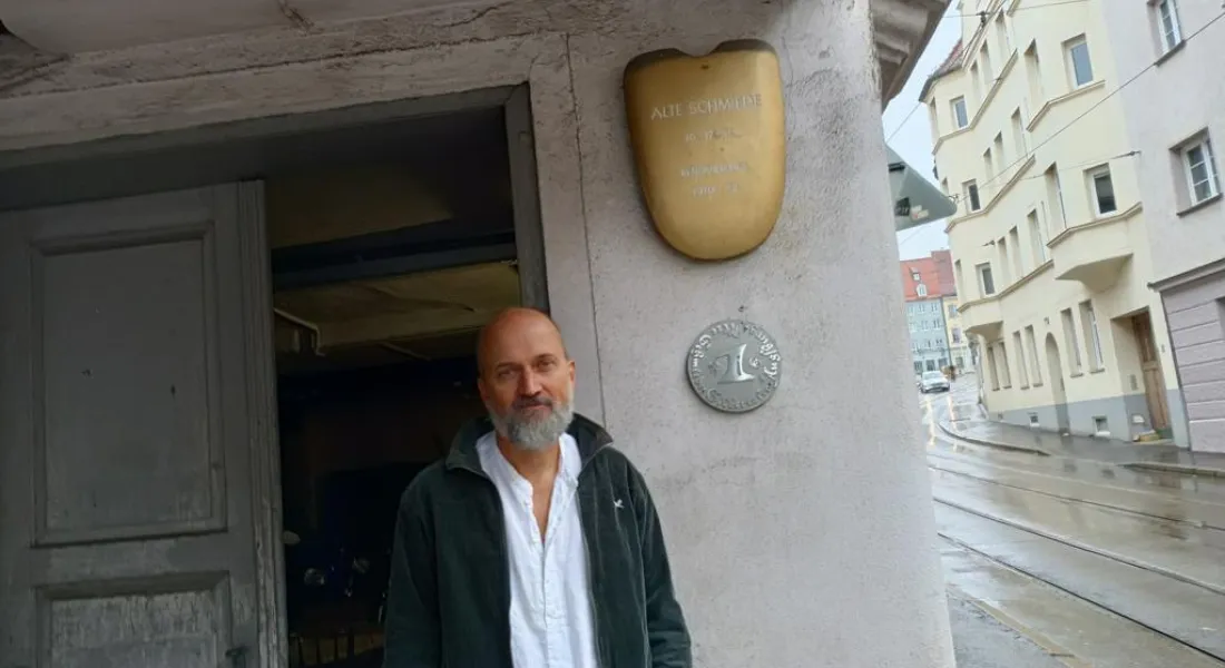 Männliche Person im Eingang eines alten Hauses mit Messingschild