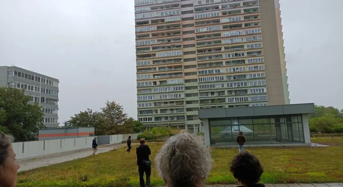 Menschen blicken zu einem grauen Hochhaus an Regentag
