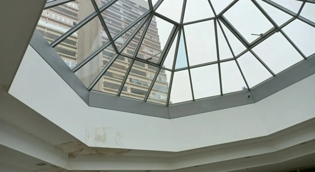 Blick durch eine Glaskuppel auf ein graues Hochhaus