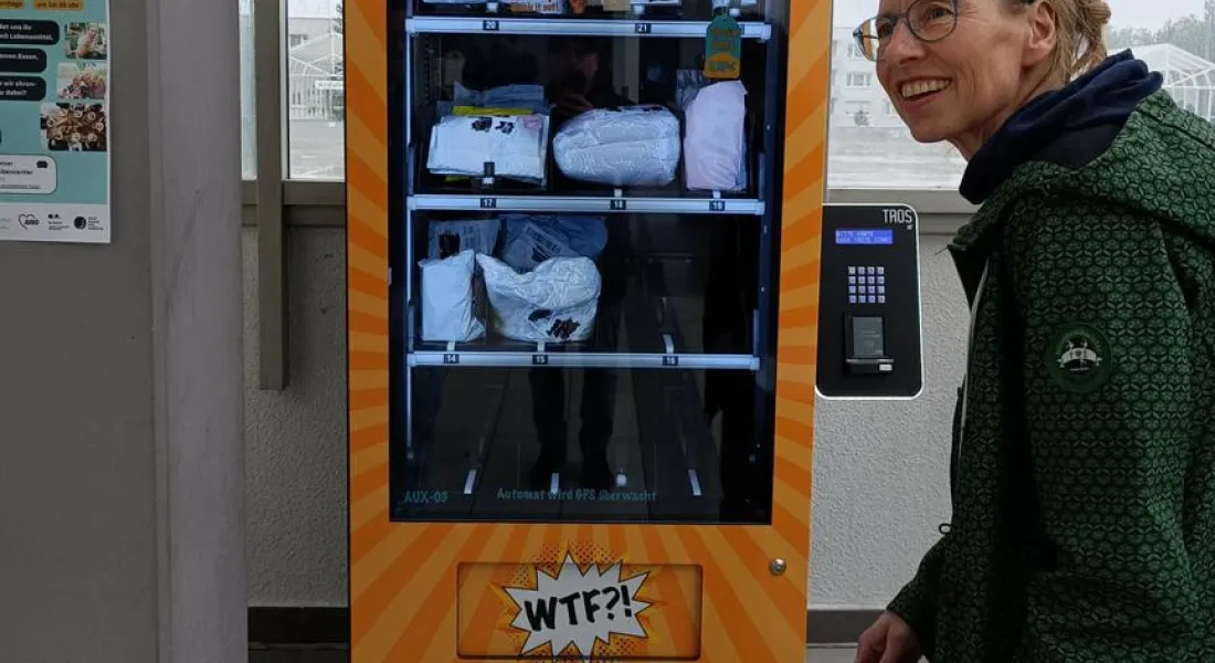 Weibliche Person, lachend, vor einem Automaten mit der Aufschrift »WTF«