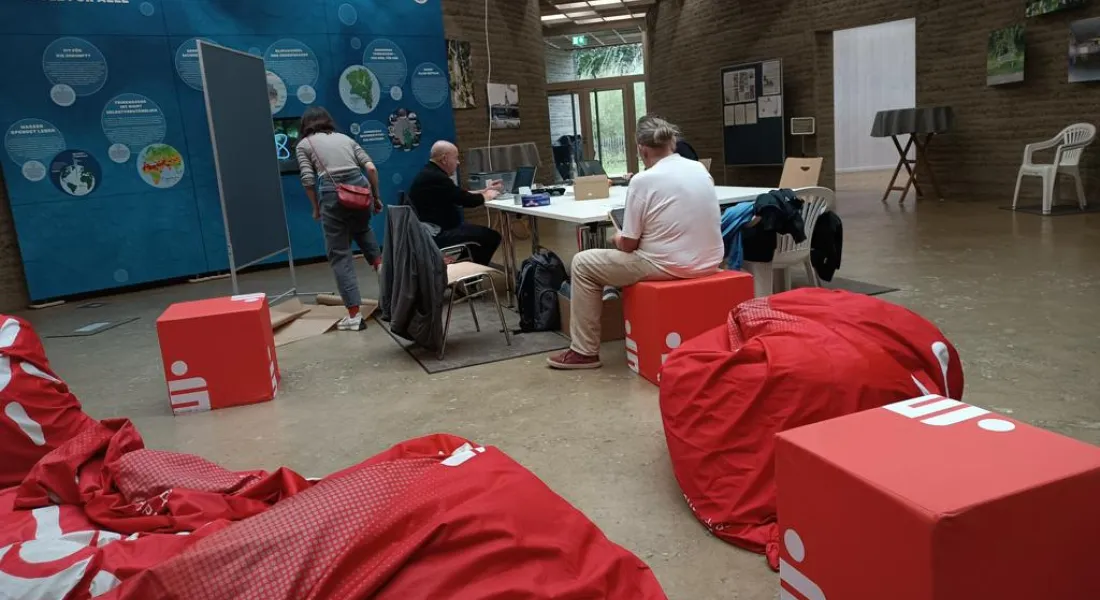 Menschen mit Laptops am Tisch, umgeben von Sitzkissen