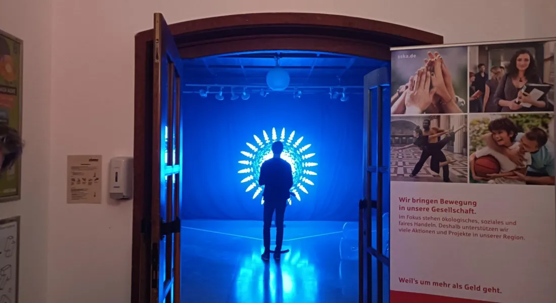 Blick durch eine offene Türe auf eine Person vor einer Lichtinstallation