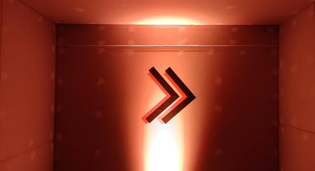 Ein beleuchteter Doppelwinkel (Fast-Forward-Symbol) als Wegweiser in einer Wandnische