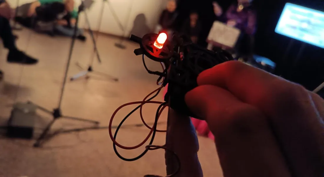 Eine Hand hält ein undefinierbares Gerät mit LED und Kabeln