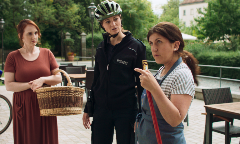 Verkäuferin Lieselotte (Lisa Grötsch, rechts) erklärt der Dorfpolizistin Nadine (Barbara Weiß, Mitte) und Magdalena (Christina Baumer, links) was in den vergangenen Monaten alles in Hundsling geschehen ist. ©Stonewood Film e.V.